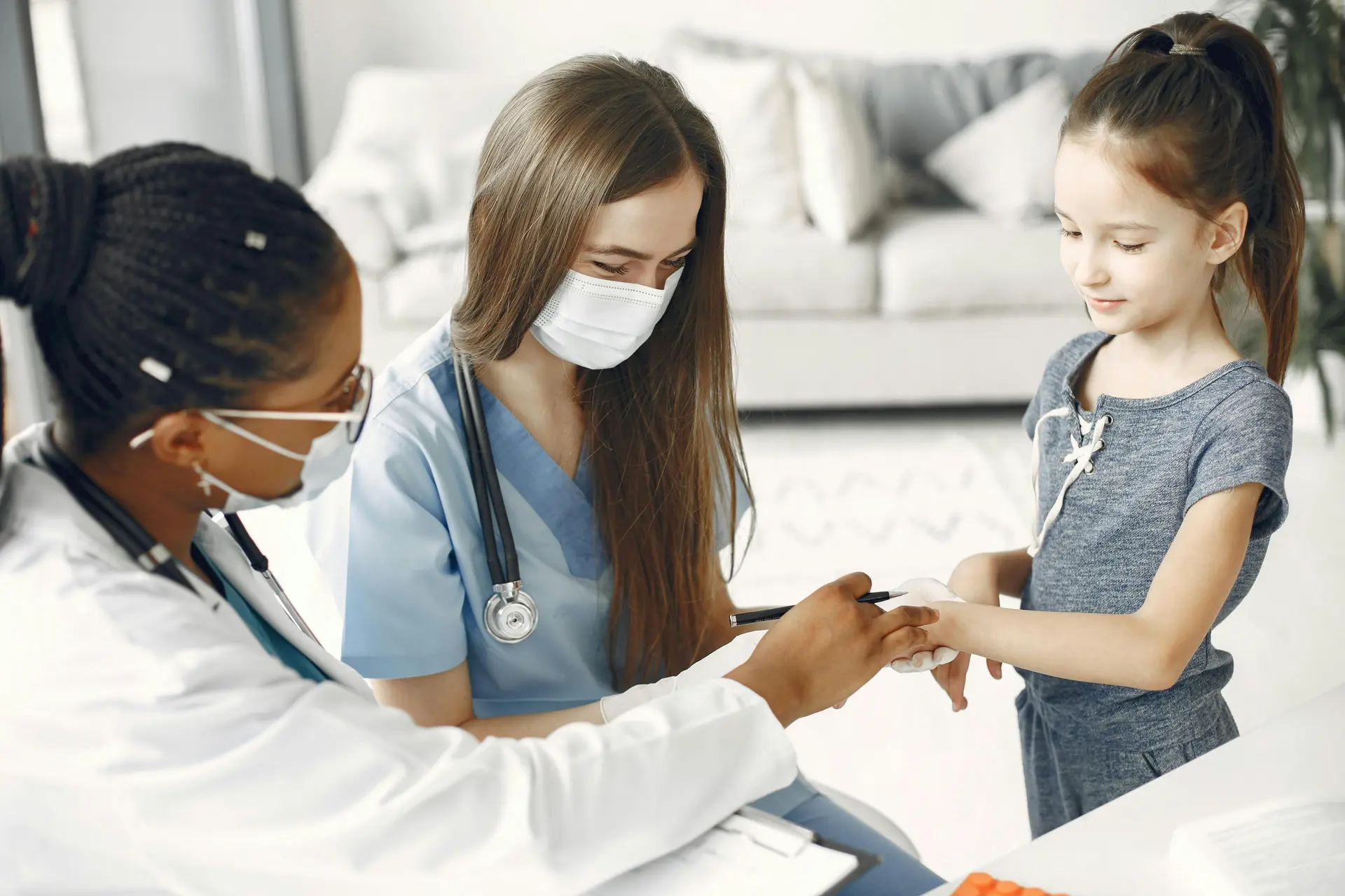 A physician examines a young patient while a second medical staff member observes, as part of her immigration medical exam.