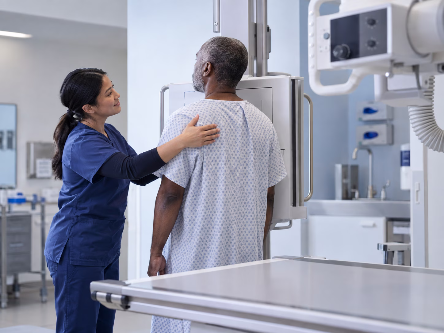 a radiology technician helping a patient position for a chest X-ray in a modern radiography room.